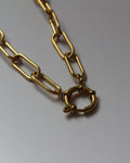 A gold-toned chain necklace with elongated paperclip-style links and a small interlocking ring clasp, photographed on a plain light background.